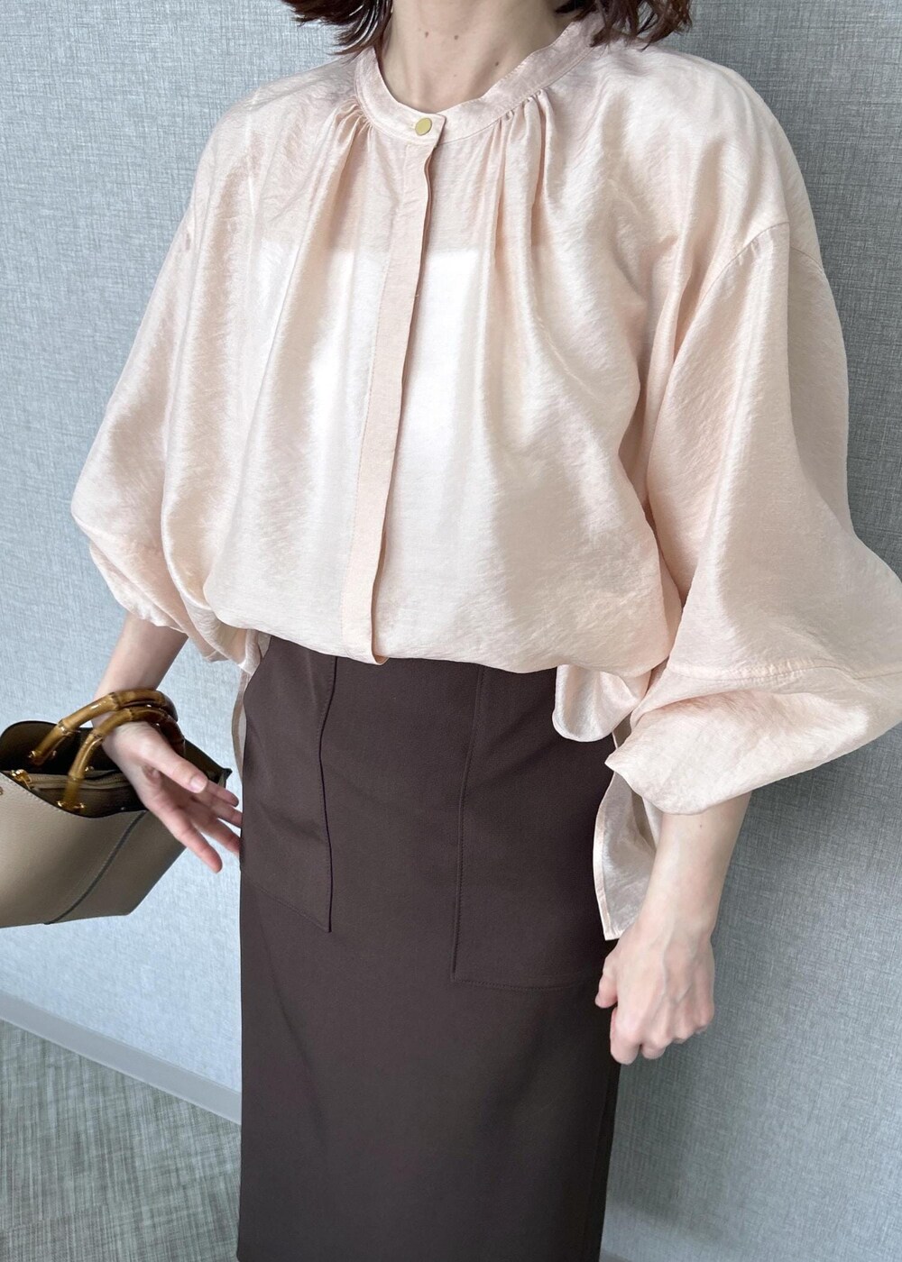 ブラック系のパンプス、ベージュ系のハンドバッグ、ブラウン系のスカートを着用したレディースの冬コーディネートの5枚目の写真