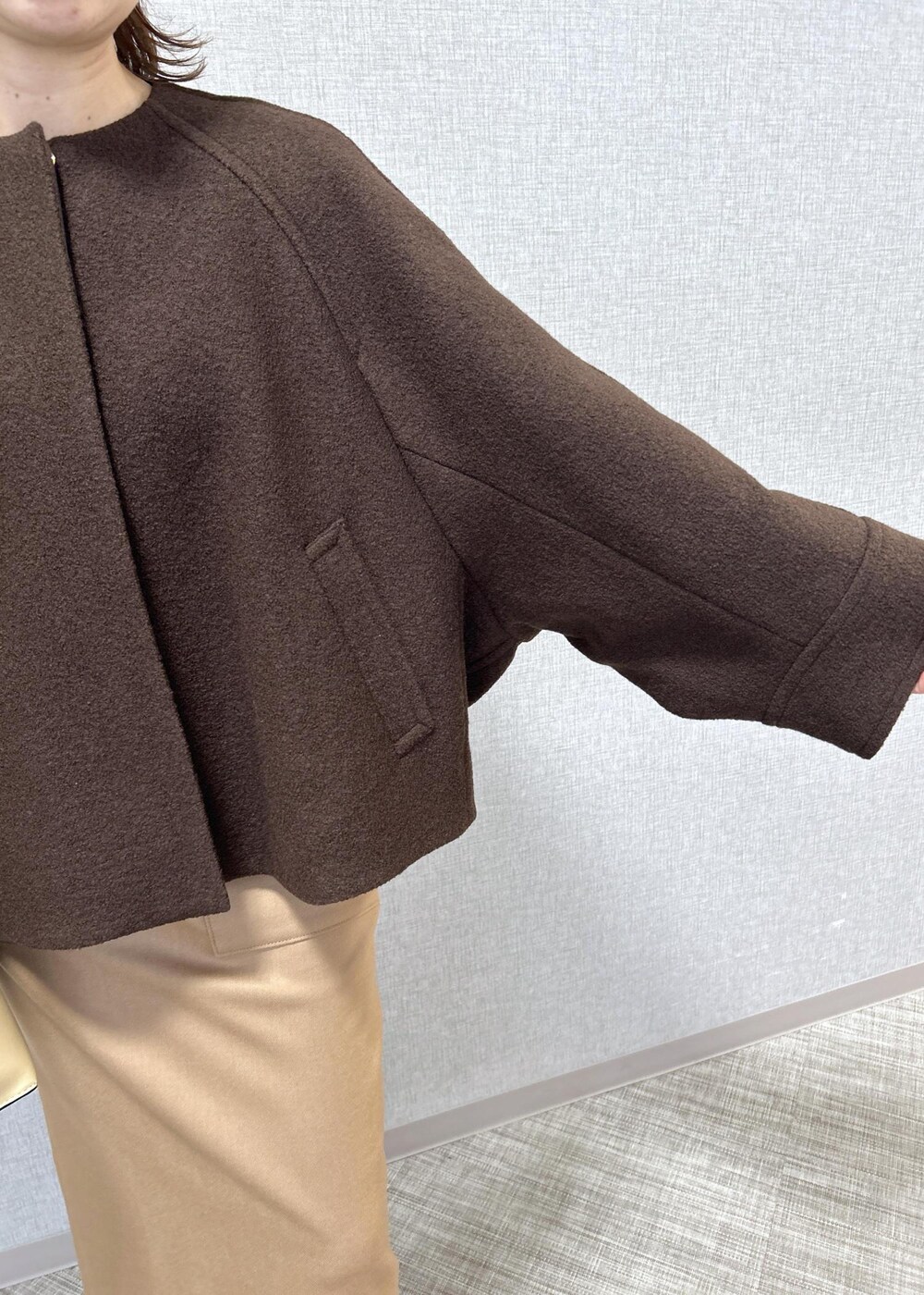 ベージュ系のトートバッグ、ブラック系のブーツ、ベージュ系のスカートを着用したレディースの秋コーディネートの7枚目の写真