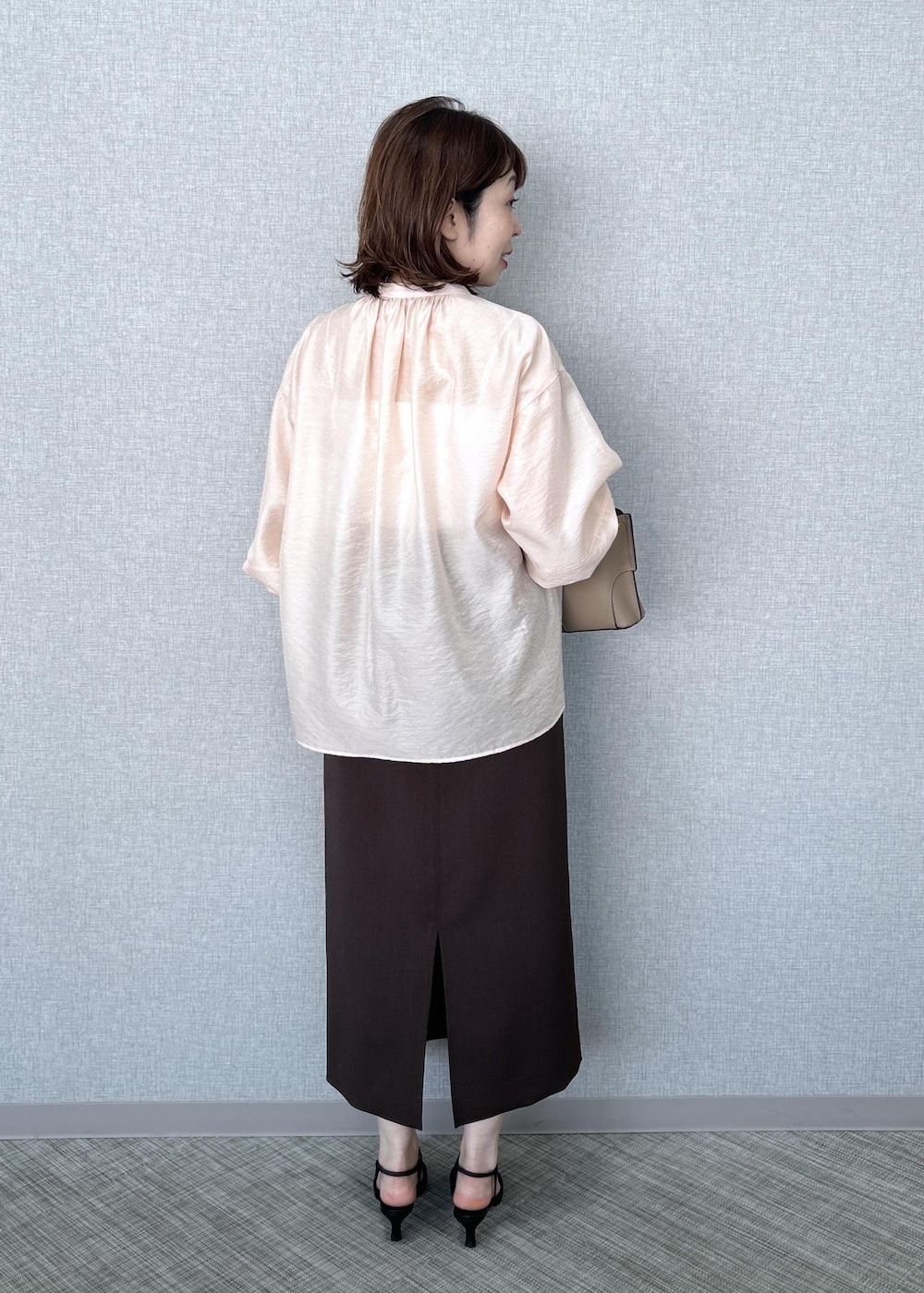 ブラック系のパンプス、ベージュ系のハンドバッグ、ブラウン系のスカートを着用したレディースの冬コーディネートの4枚目の写真