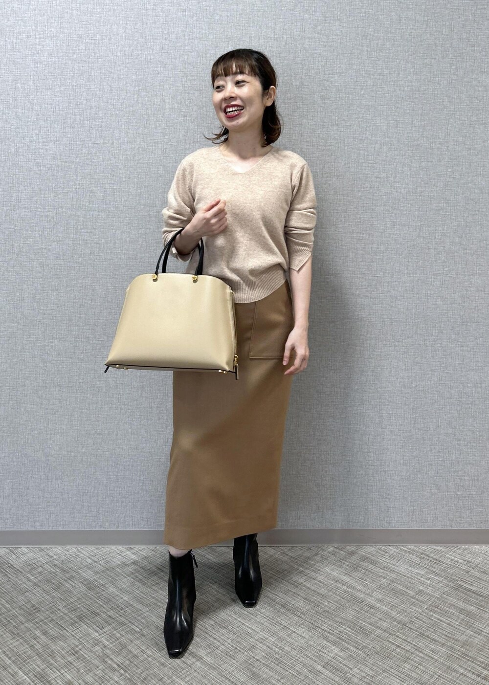 ベージュ系のトートバッグ、ブラック系のブーツ、ベージュ系のスカートを着用したレディースの秋コーディネートの4枚目の写真