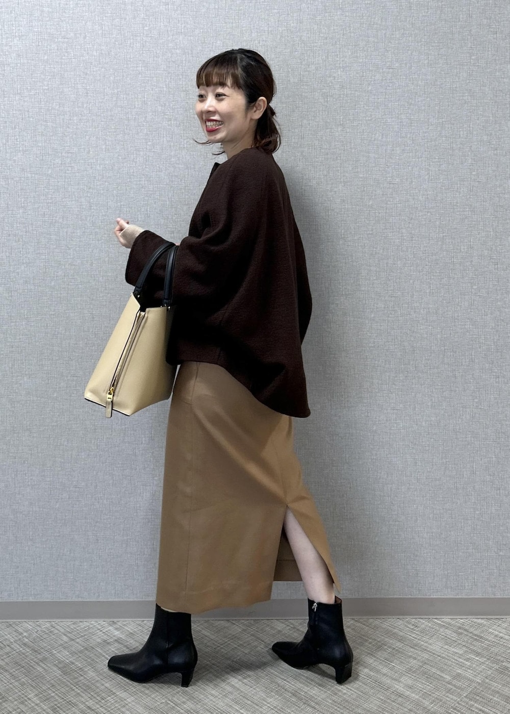 ベージュ系のトートバッグ、ブラック系のブーツ、ベージュ系のスカートを着用したレディースの秋コーディネートの3枚目の写真