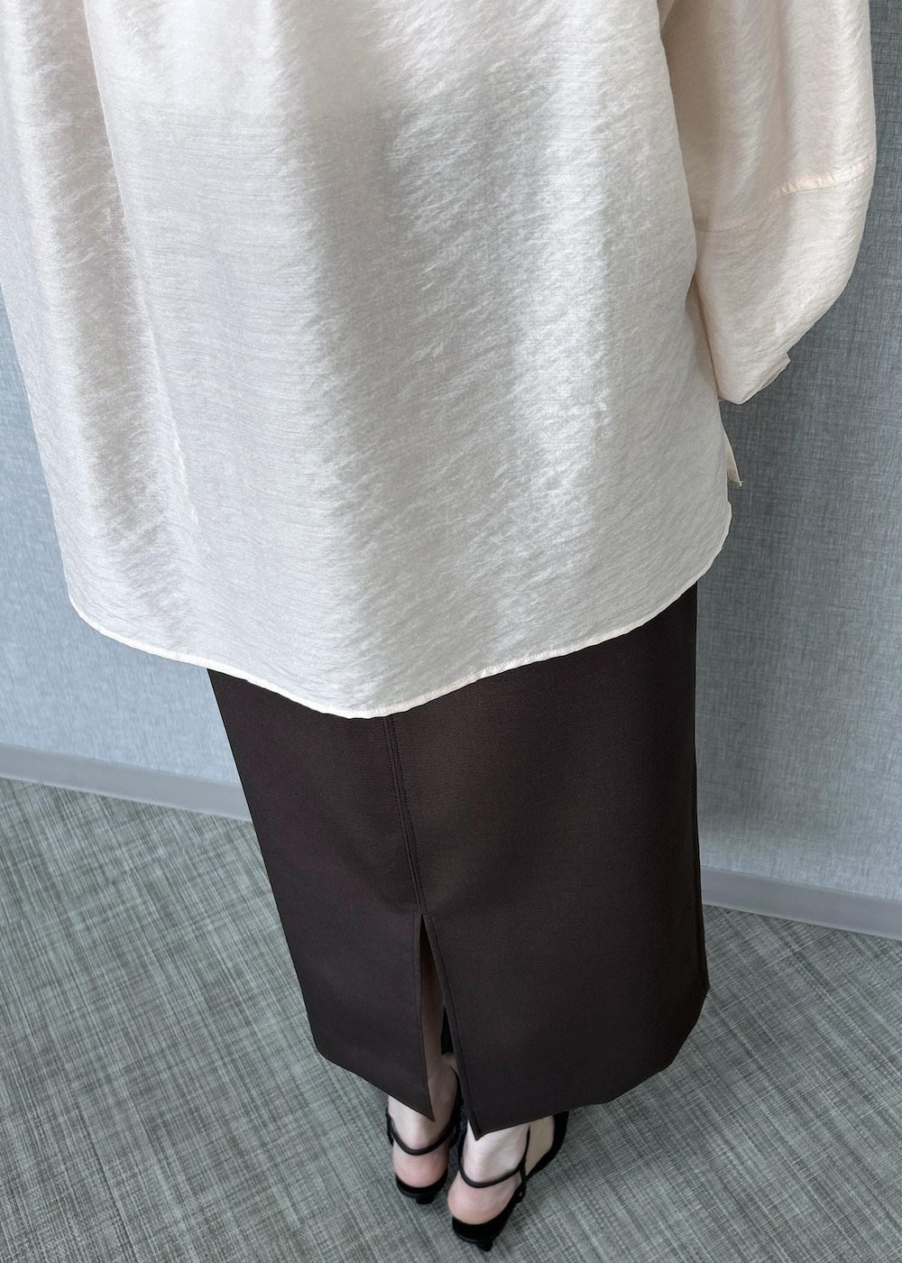 ブラック系のパンプス、ベージュ系のハンドバッグ、ブラウン系のスカートを着用したレディースの冬コーディネートの7枚目の写真