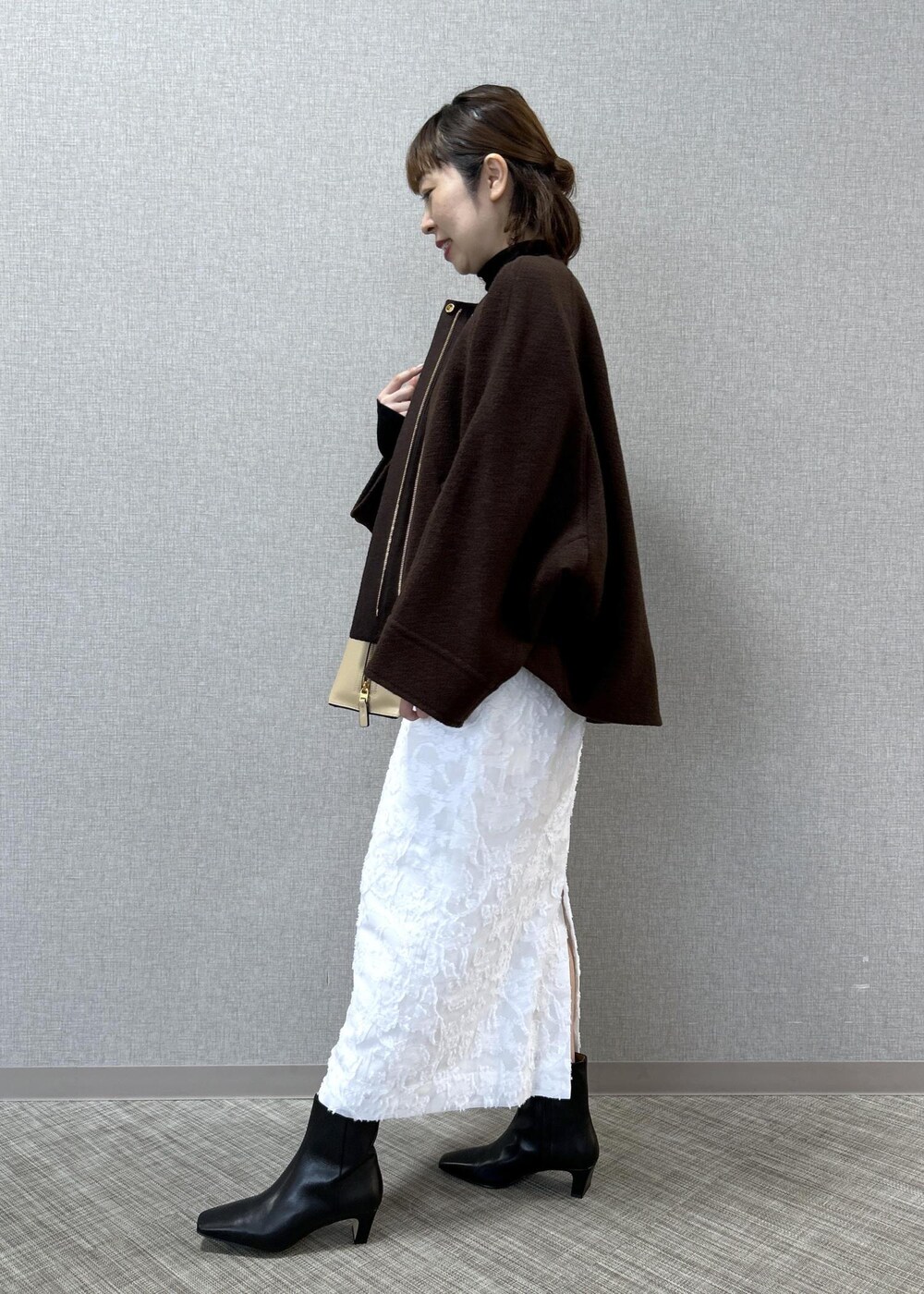 ベージュ系のトートバッグ、ブラック系のブーツ、ホワイト系のスカートを着用したレディースの秋コーディネートの3枚目の写真