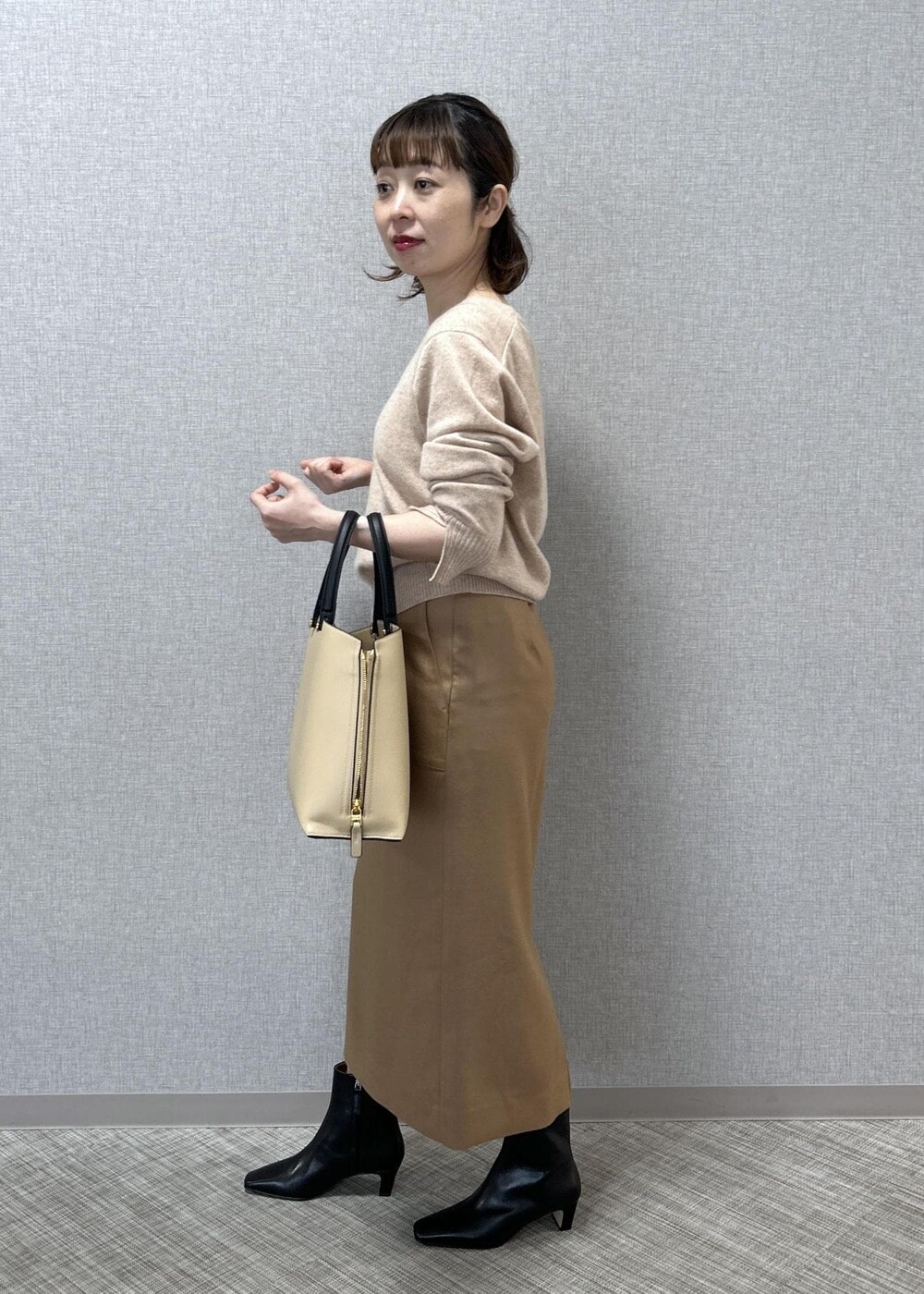 ベージュ系のトートバッグ、ブラック系のブーツ、ベージュ系のスカートを着用したレディースの秋コーディネートの5枚目の写真