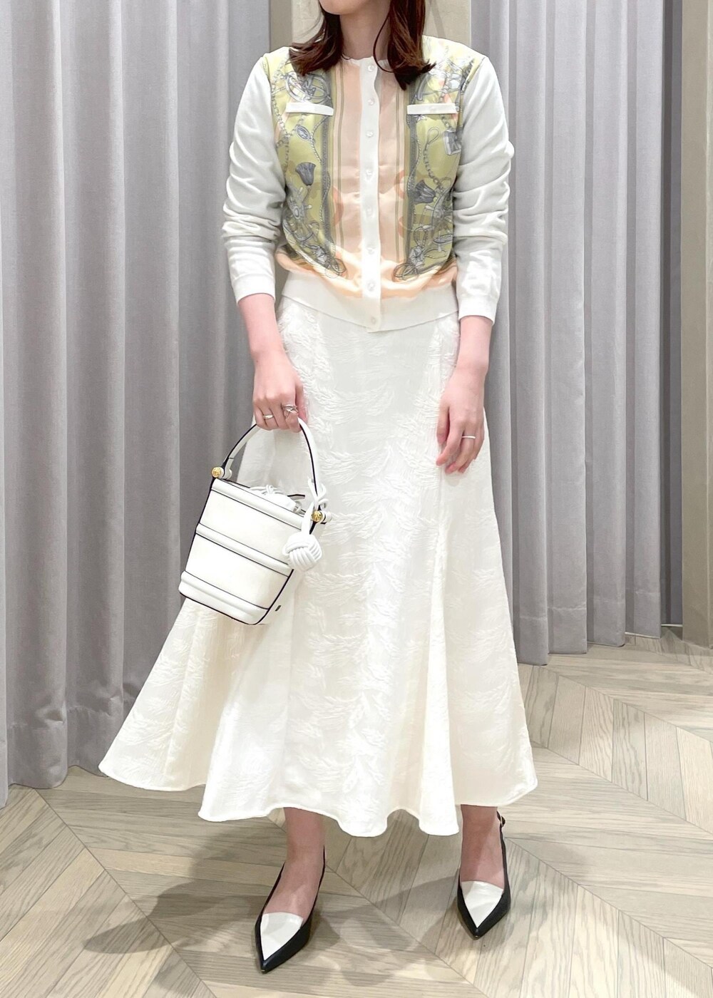 ホワイト系のハンドバッグ、ホワイト系のカーディガン/ボレロ、ブラック系のパンプスを着用したレディースの春コーディネートの4枚目の写真