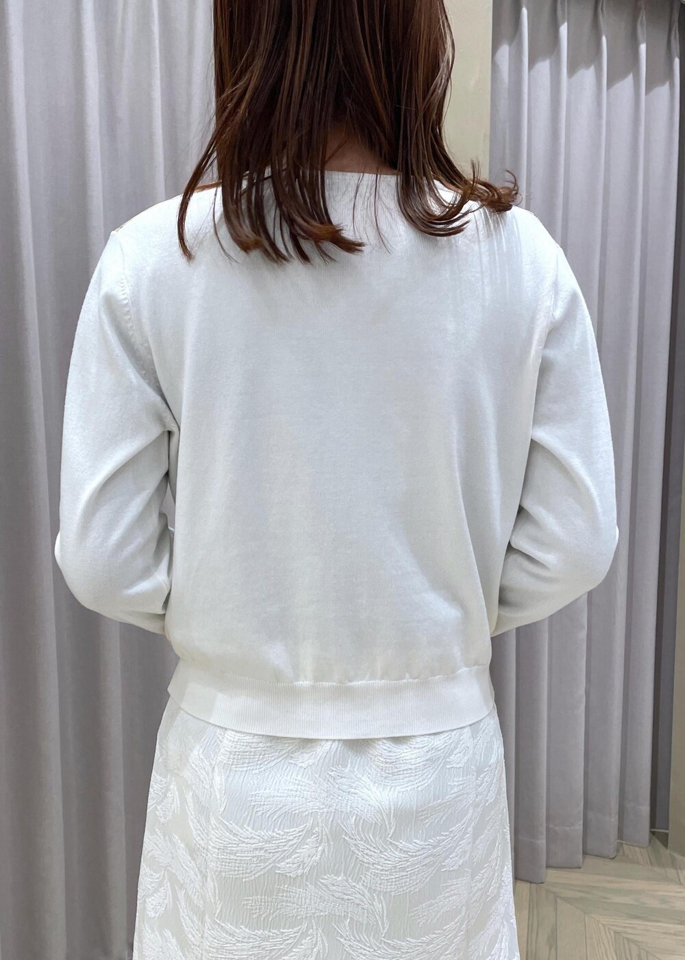 ホワイト系のハンドバッグ、ホワイト系のカーディガン/ボレロ、ブラック系のパンプスを着用したレディースの春コーディネートの7枚目の写真