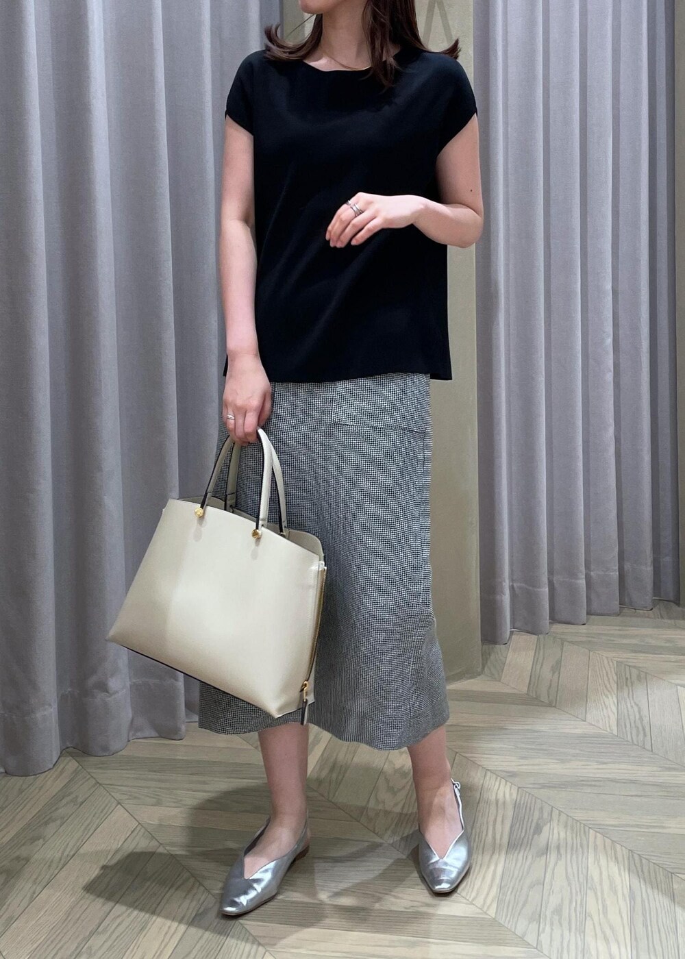 ベージュ系のハンドバッグ、シルバー系のパンプス、ブラック系のニット/セーターを着用したレディースの春コーディネートの7枚目の写真