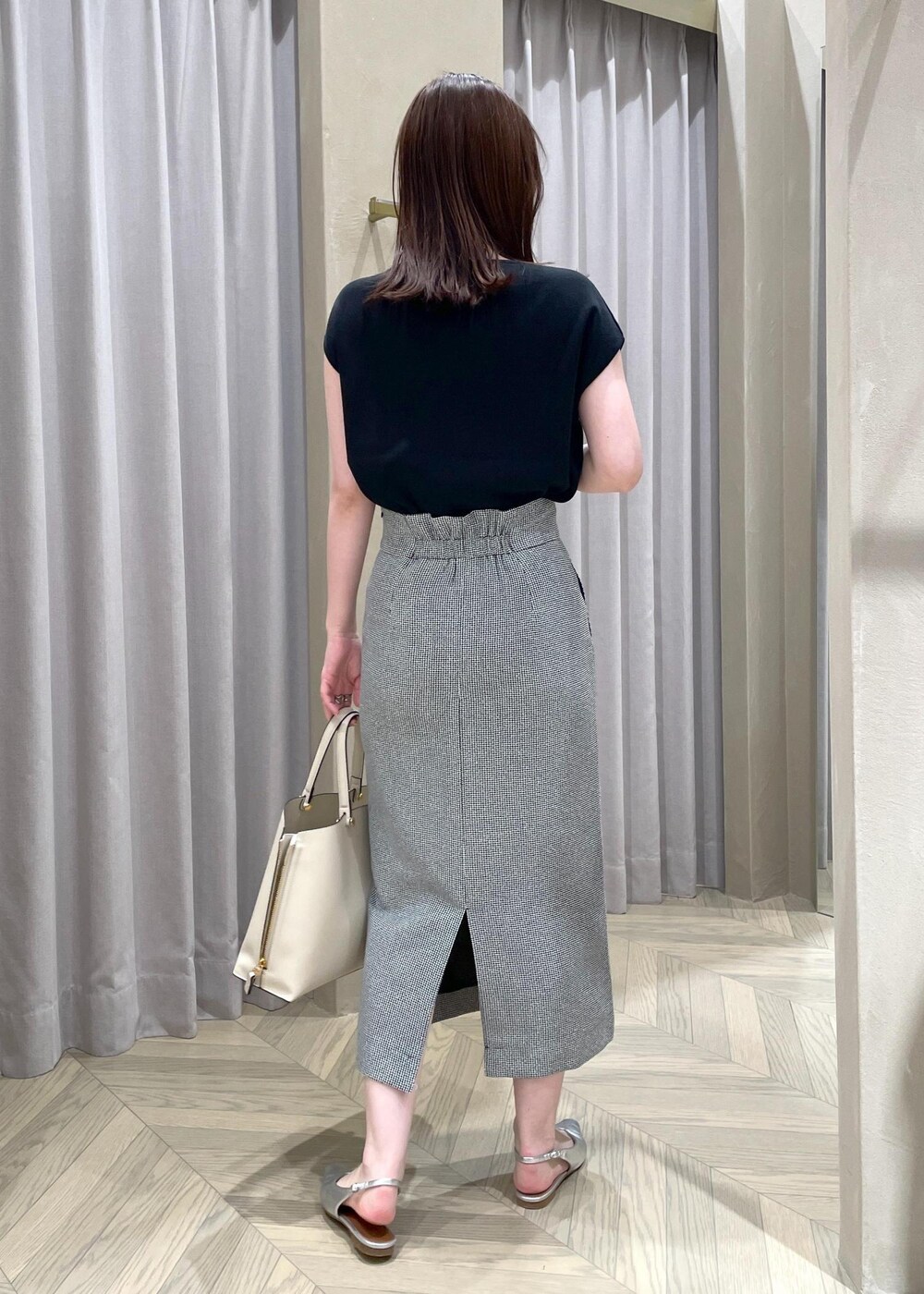 ベージュ系のハンドバッグ、シルバー系のパンプス、ブラック系のニット/セーターを着用したレディースの春コーディネートの3枚目の写真