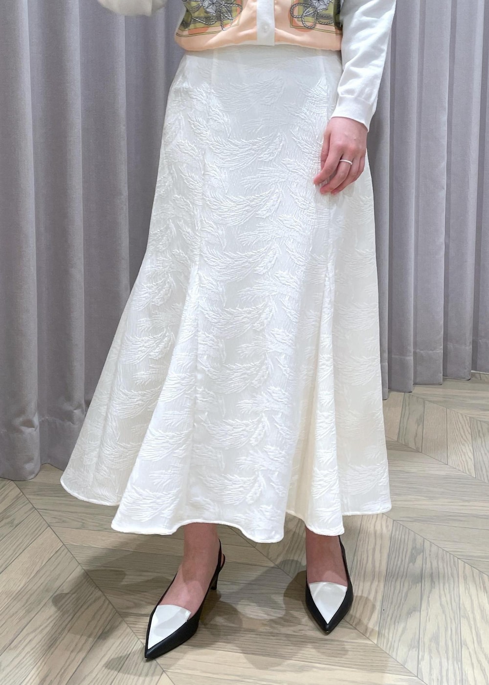 ホワイト系のハンドバッグ、ホワイト系のカーディガン/ボレロ、ブラック系のパンプスを着用したレディースの春コーディネートの8枚目の写真