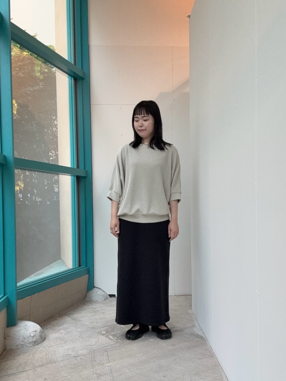 ベージュ系のTシャツ/カットソー、ブラック系のスカートを着用したレディースの秋コーディネートの2枚目の写真