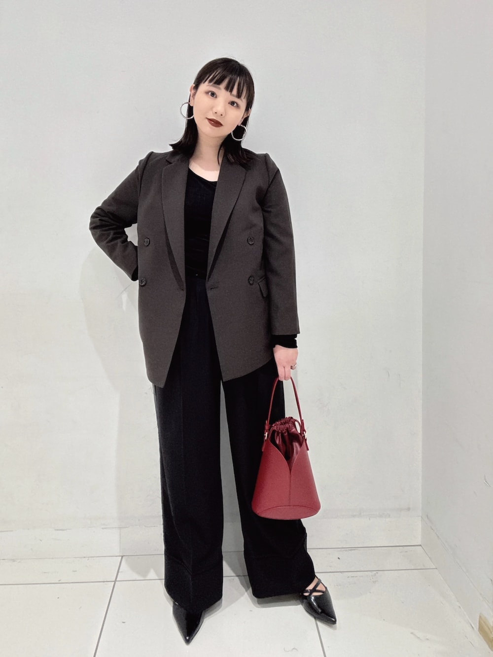 ブラウン系のその他アウター、ブラック系のその他パンツ、レッド系のハンドバッグを着用したレディースの秋コーディネートの2枚目の写真
