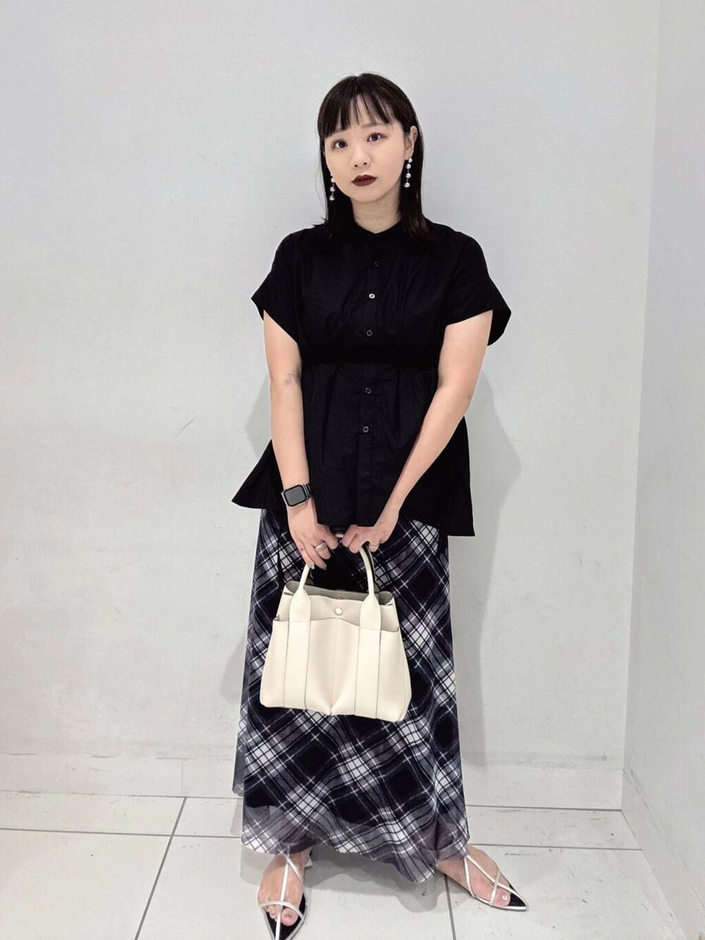 ホワイト系のトートバッグ、シルバー系のサンダル、ブラック系のシャツ/ブラウスを着用したレディースの夏コーディネートの2枚目の写真