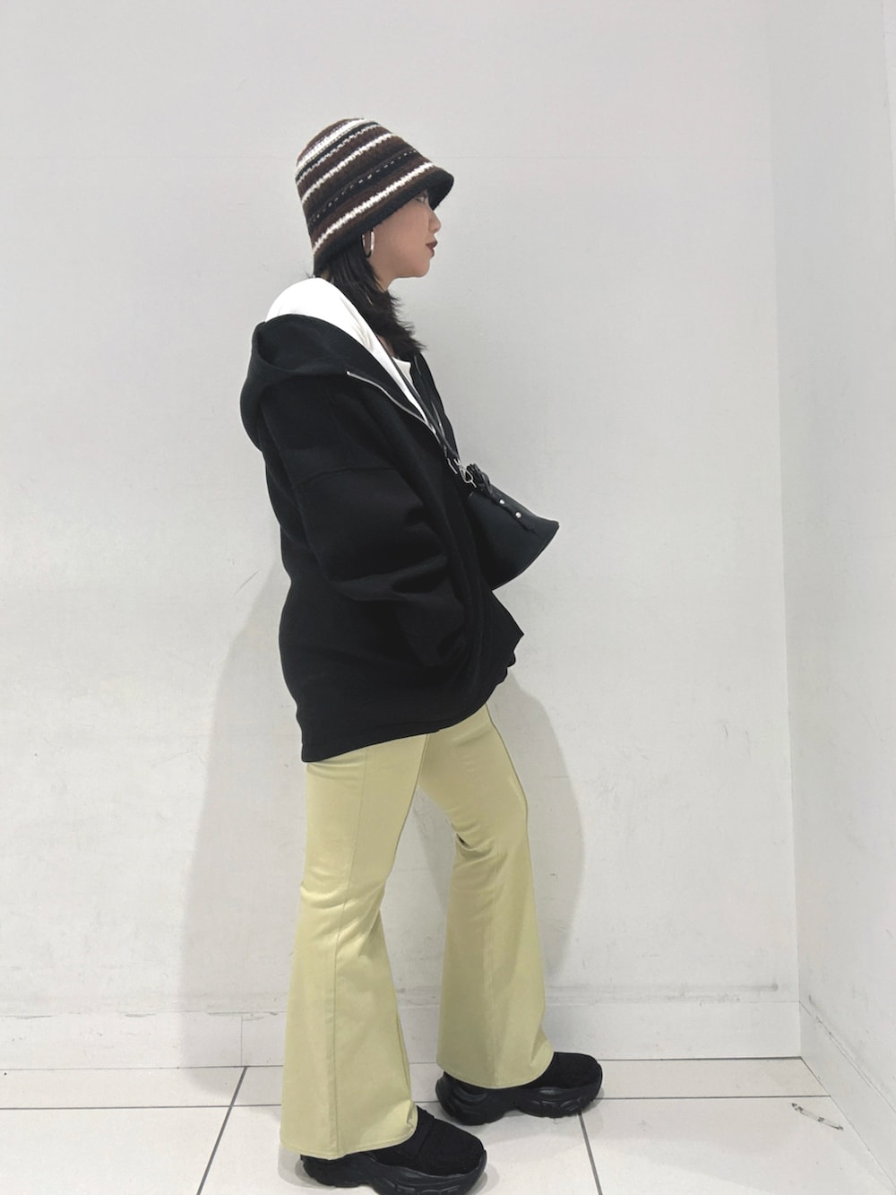 ブラック系のパーカー、ブラック系のショルダーバッグ、ホワイト系のTシャツ/カットソーを着用したレディースの冬コーディネートの3枚目の写真