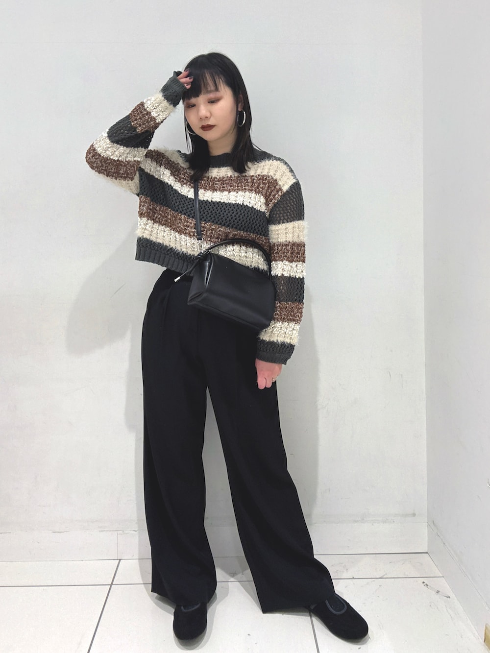 ブラック系のニット/セーター、ブラック系のスラックス、ブラック系のハンドバッグを着用したレディースの冬コーディネートの2枚目の写真