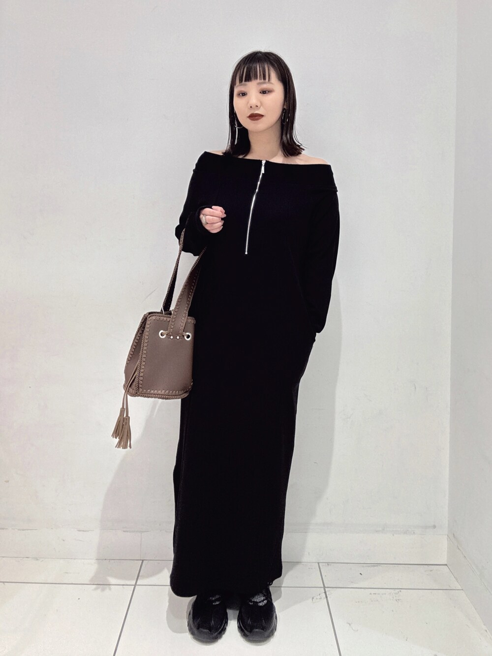 ブラック系のワンピース、ブラック系のスニーカー、ブラウン系のショルダーバッグを着用したレディースの秋コーディネートの3枚目の写真