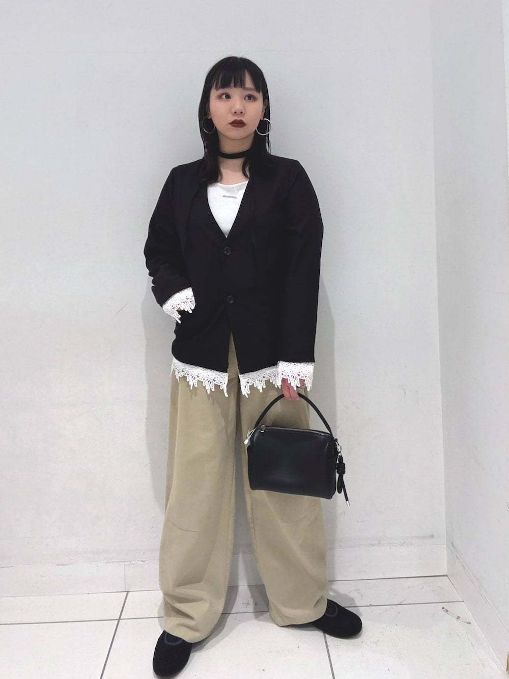 ブラック系のノーカラージャケット、ホワイト系のTシャツ/カットソー、ブラック系のハンドバッグを着用したレディースの冬コーディネートの3枚目の写真