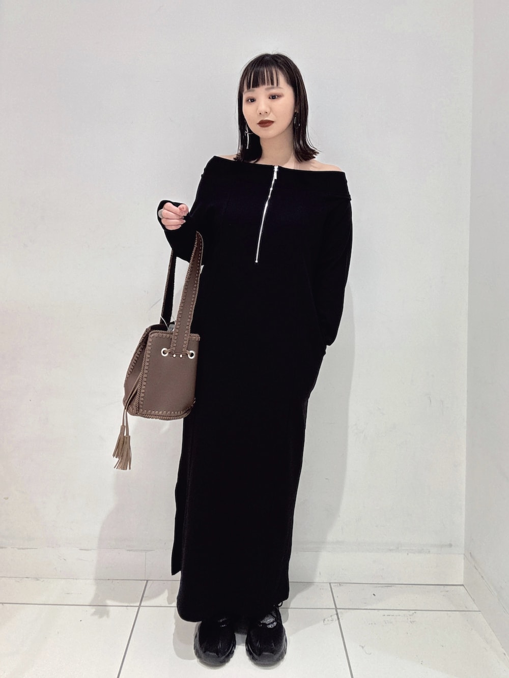 ブラック系のワンピース、ブラック系のスニーカー、ブラウン系のショルダーバッグを着用したレディースの秋コーディネートの2枚目の写真