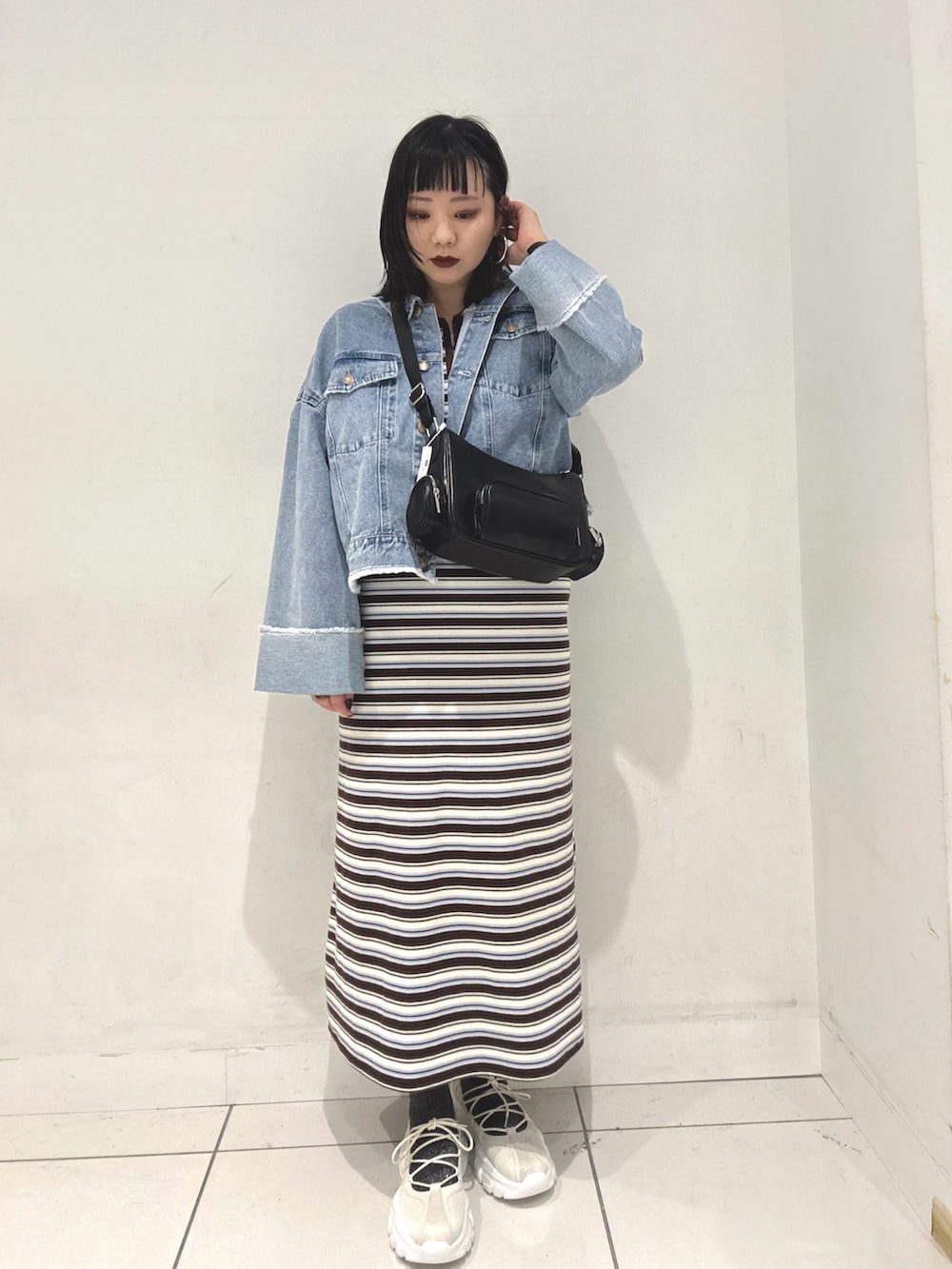 ブラウン系のワンピース、ブルー系のデニムジャケット、ホワイト系のスニーカーを着用したレディースの春コーディネートの2枚目の写真