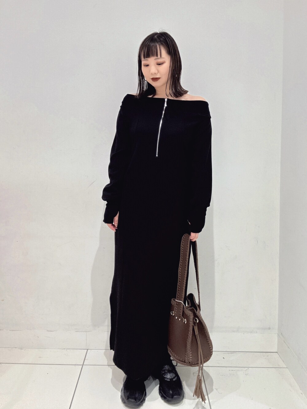 ブラック系のワンピース、ブラック系のスニーカー、ブラウン系のショルダーバッグを着用したレディースの秋コーディネートの4枚目の写真