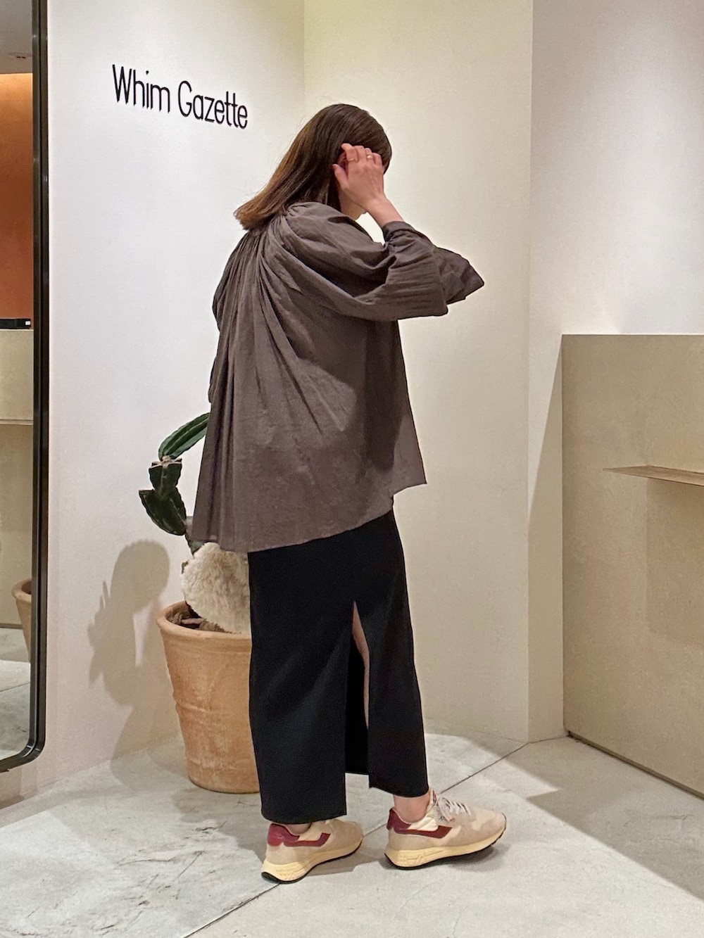 ブラウン系のシャツ/ブラウス、ブラック系のスカート、ホワイト系のハンドバッグを着用したレディースの秋コーディネートの4枚目の写真