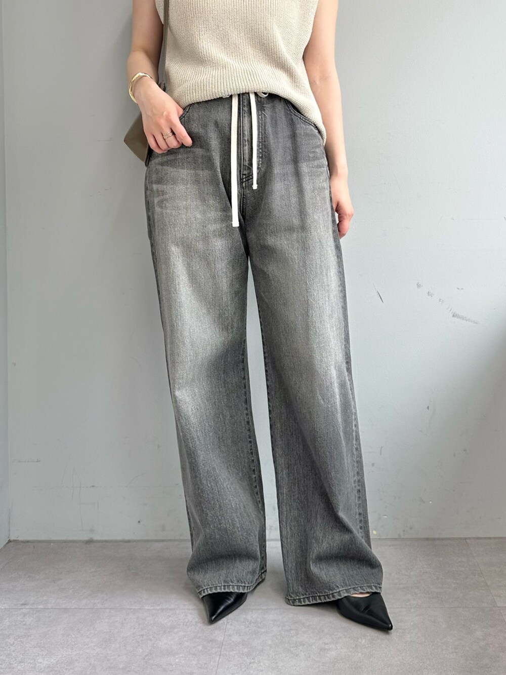 グレー系のデニムパンツ、ベージュ系のニット/セーター、ブラウン系のショルダーバッグを着用したレディースの春コーディネートの7枚目の写真