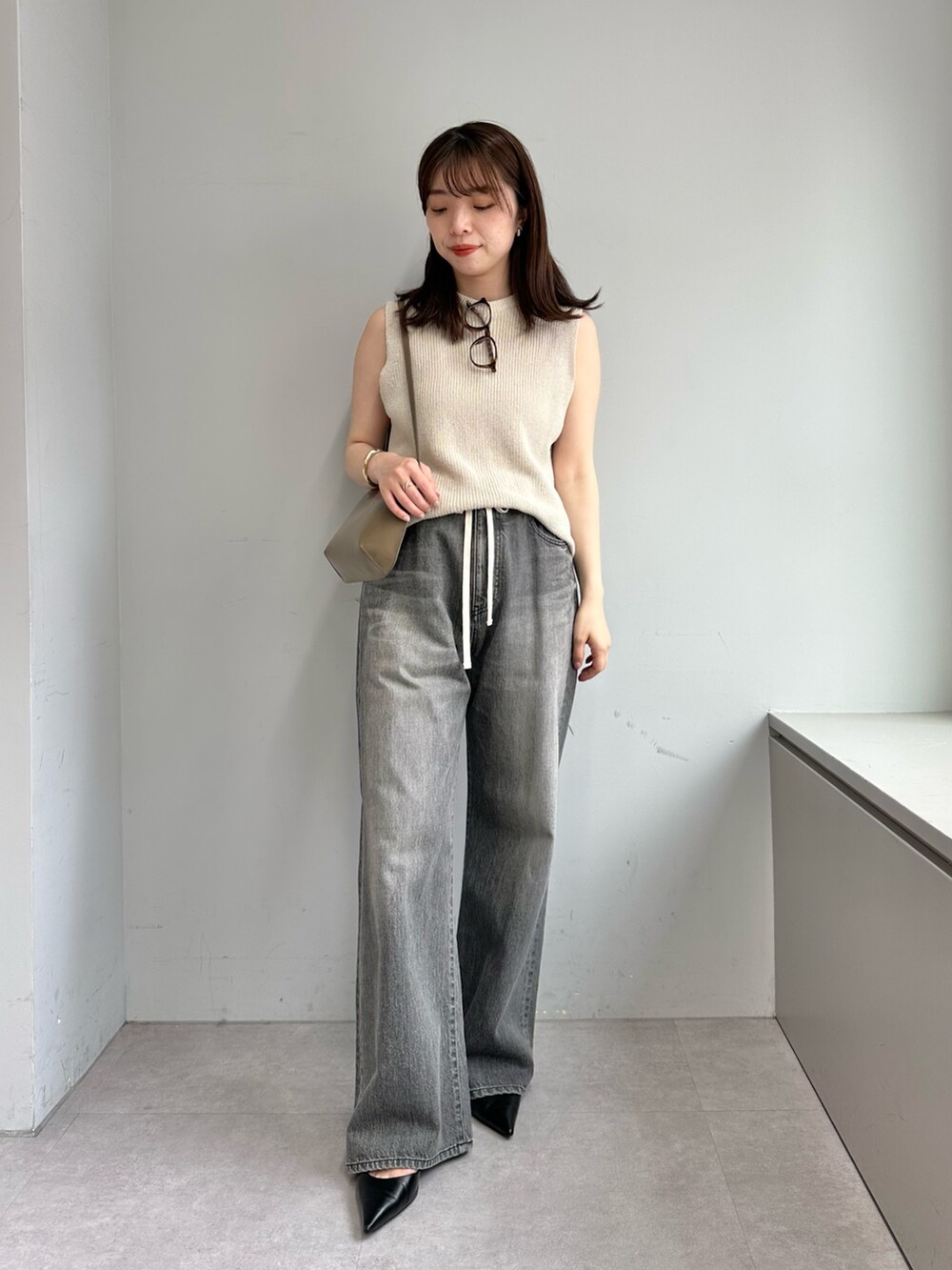 グレー系のデニムパンツ、ベージュ系のニット/セーター、ブラウン系のショルダーバッグを着用したレディースの春コーディネートの5枚目の写真