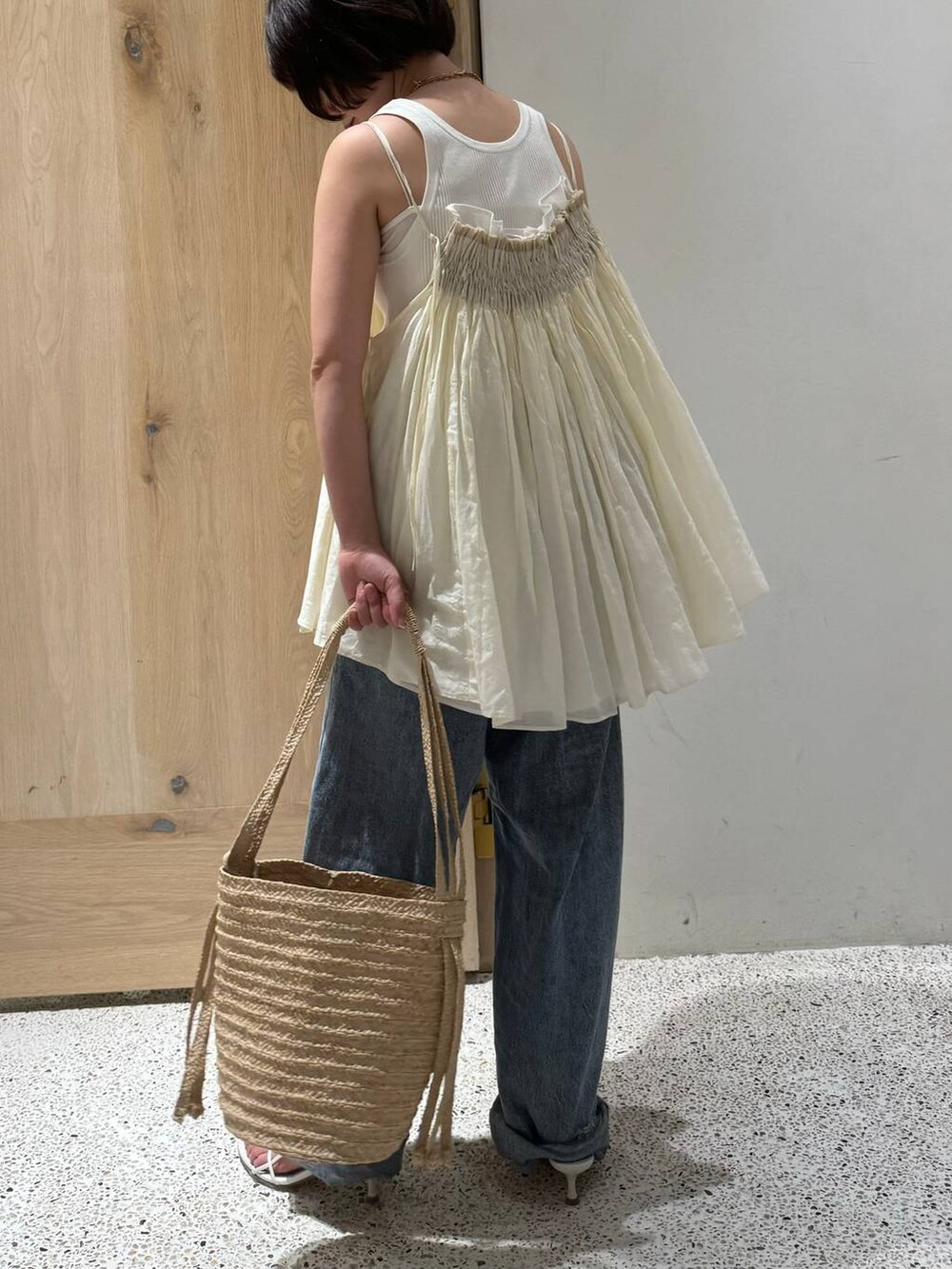 ホワイト系のタンクトップ、ホワイト系のキャミソール、ブルー系のデニムパンツを着用したレディースの春コーディネートの3枚目の写真