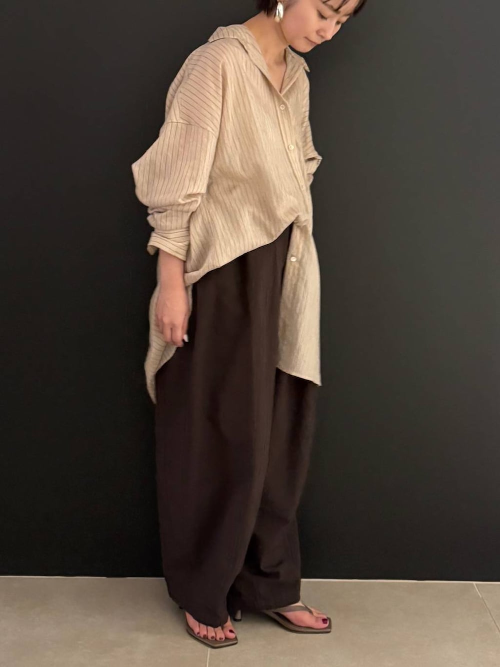 ブラウン系のその他パンツ、ベージュ系のシャツ/ブラウス、シルバー系のピアス(両耳用)を着用したレディースの夏コーディネートの3枚目の写真