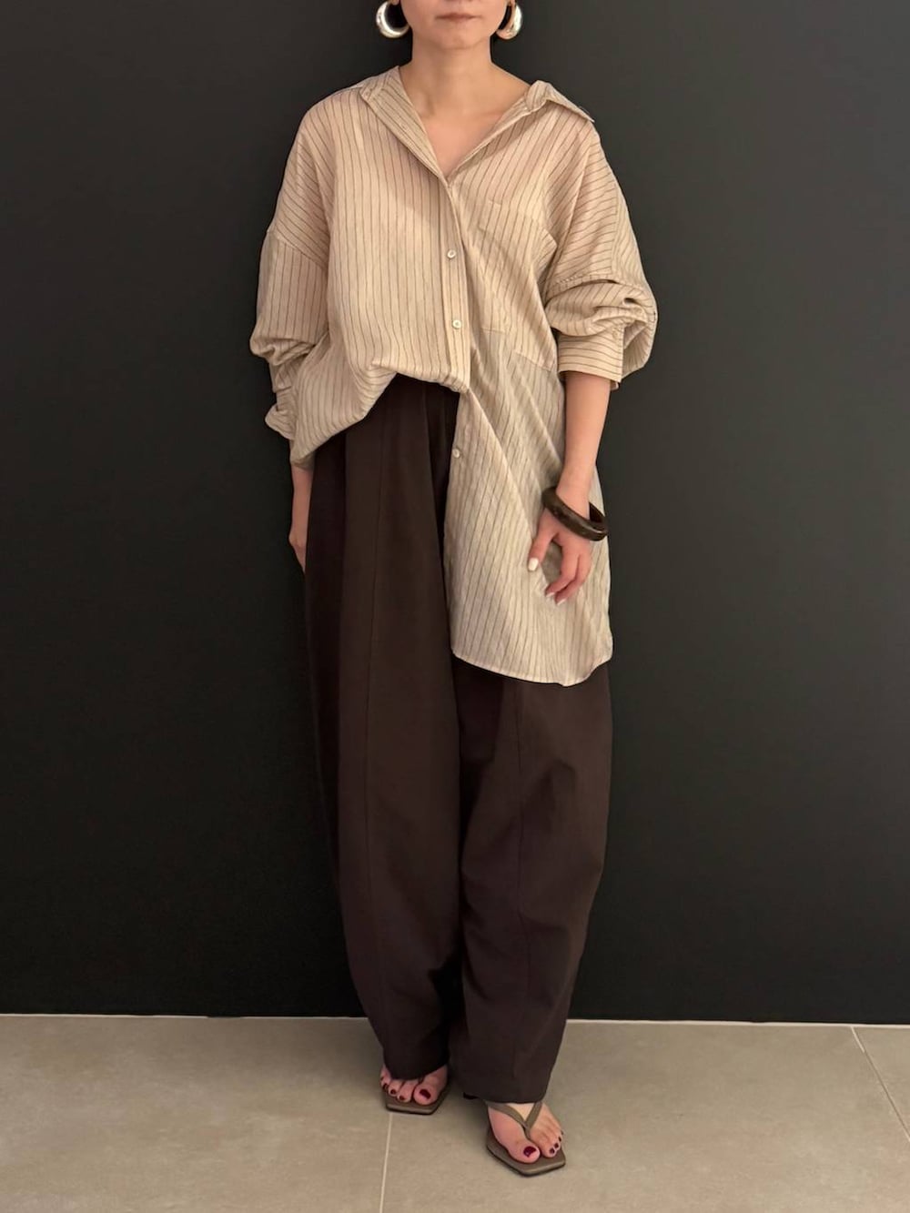 ブラウン系のその他パンツ、ベージュ系のシャツ/ブラウス、シルバー系のピアス(両耳用)を着用したレディースの夏コーディネートの2枚目の写真