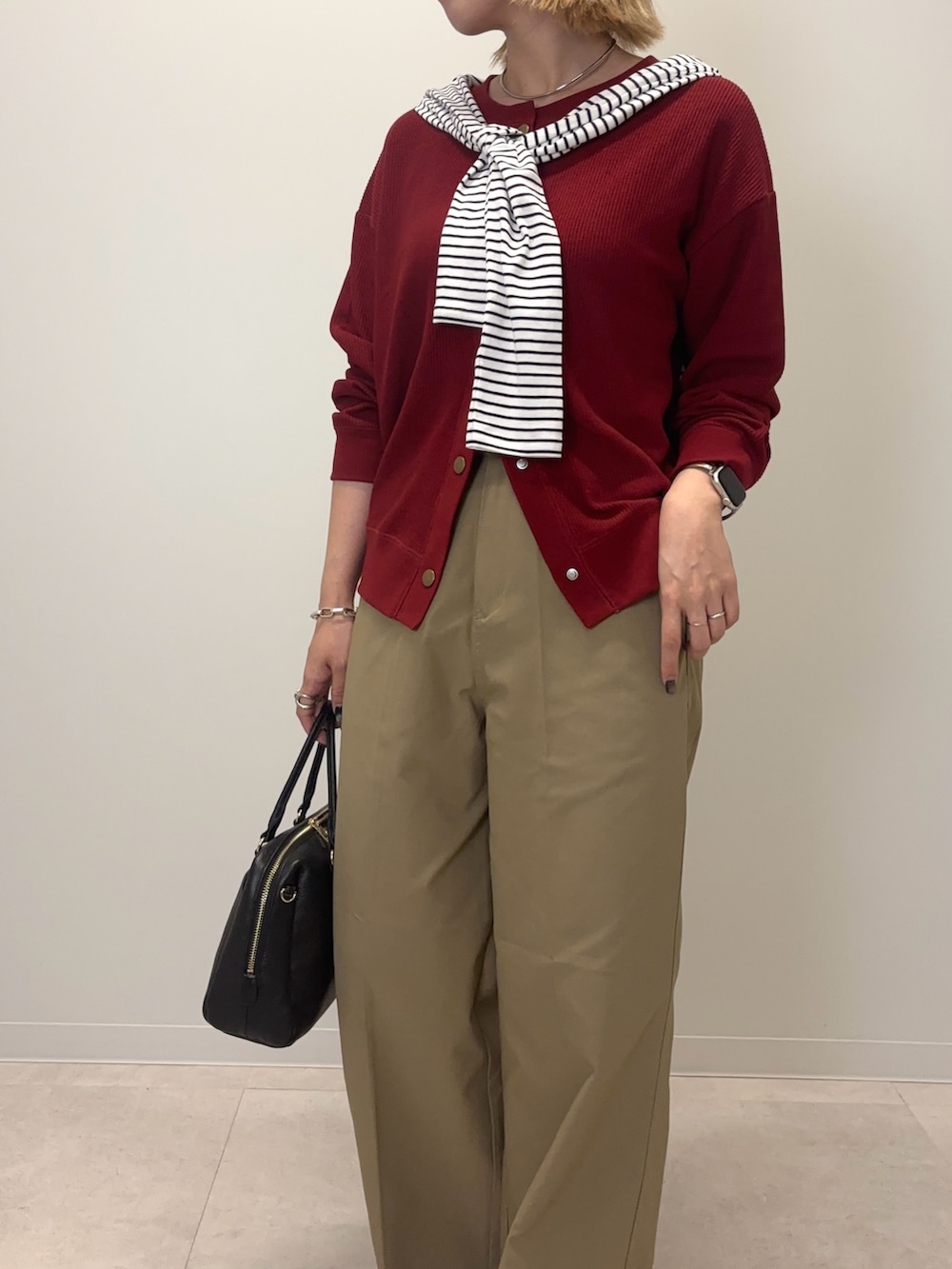 レッド系のカーディガン/ボレロ、ベージュ系のその他パンツ、ブラック系のボストンバッグを着用したレディースの秋コーディネートの6枚目の写真