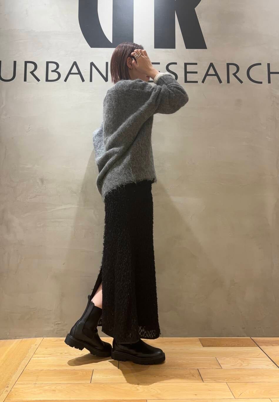 ブラック系のブーツ、グレー系のニット/セーター、ブラック系のスカートを着用したレディースの秋コーディネートの2枚目の写真