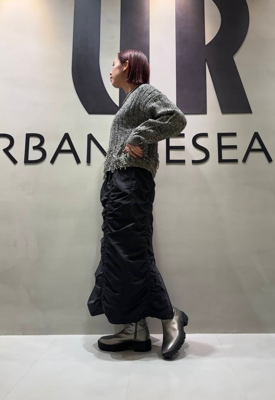 シルバー系のブーツ、ブラック系のスカート、ブラック系のニット/セーターを着用したレディースの秋コーディネートの2枚目の写真