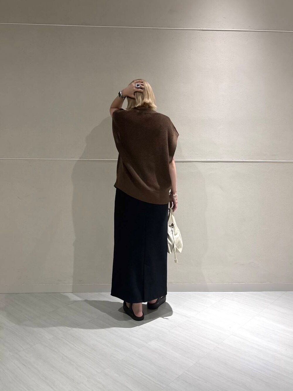 ホワイト系のキャミソール、ブラウン系のベスト、ブラック系のスカートを着用したレディースの夏コーディネートの3枚目の写真