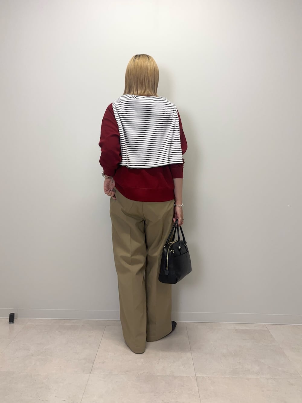 レッド系のカーディガン/ボレロ、ベージュ系のその他パンツ、ブラック系のボストンバッグを着用したレディースの秋コーディネートの3枚目の写真
