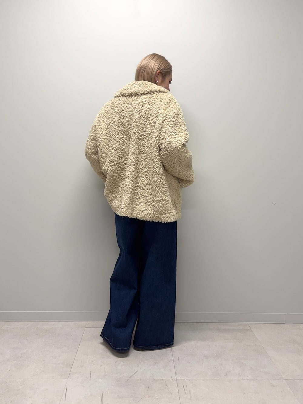 ブラック系のスニーカー、ブルー系のデニムパンツ、ホワイト系のその他アウターを着用したレディースの冬コーディネートの7枚目の写真