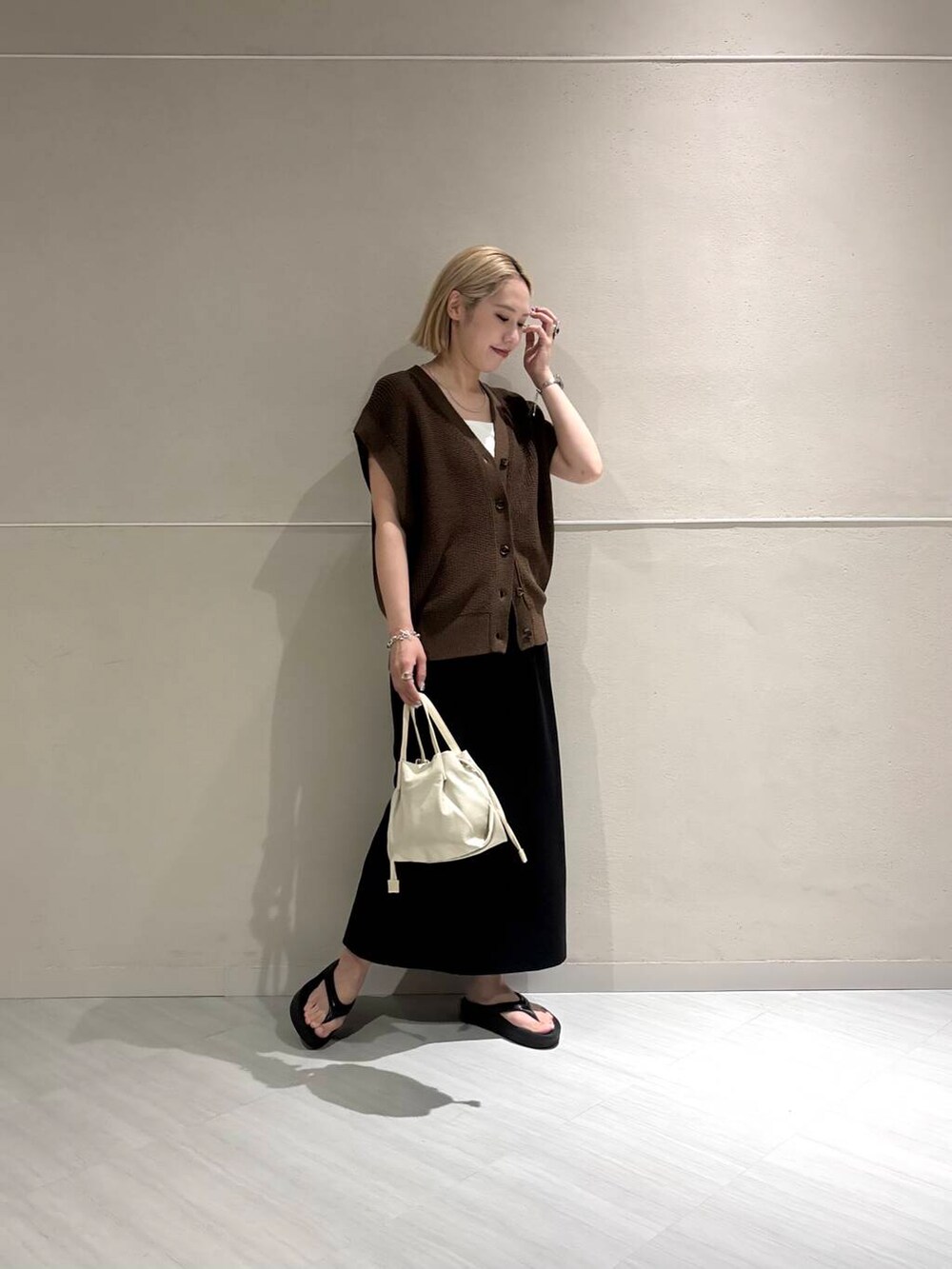 ホワイト系のキャミソール、ブラウン系のベスト、ブラック系のスカートを着用したレディースの夏コーディネートの4枚目の写真