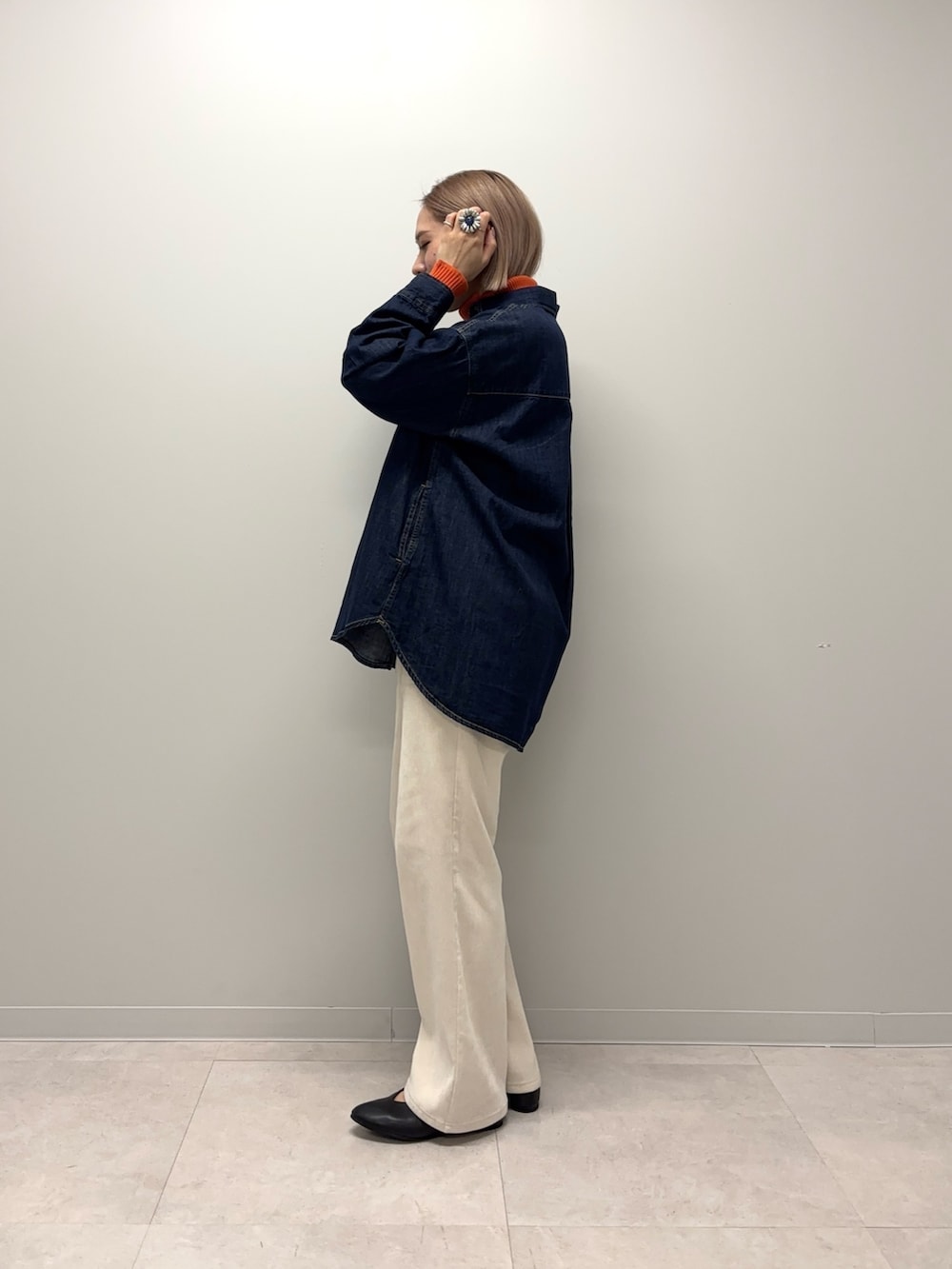 オレンジ系のニット/セーター、ブルー系のシャツ/ブラウス、ホワイト系のその他パンツを着用したレディースの冬コーディネートの5枚目の写真