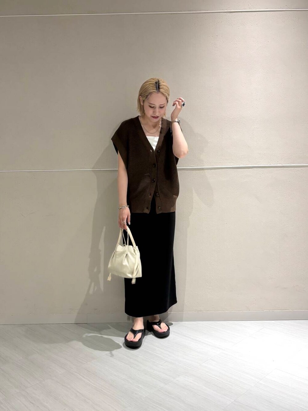 ホワイト系のキャミソール、ブラウン系のベスト、ブラック系のスカートを着用したレディースの夏コーディネートの5枚目の写真