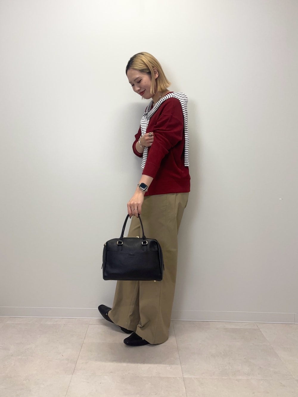 レッド系のカーディガン/ボレロ、ベージュ系のその他パンツ、ブラック系のボストンバッグを着用したレディースの秋コーディネートの2枚目の写真
