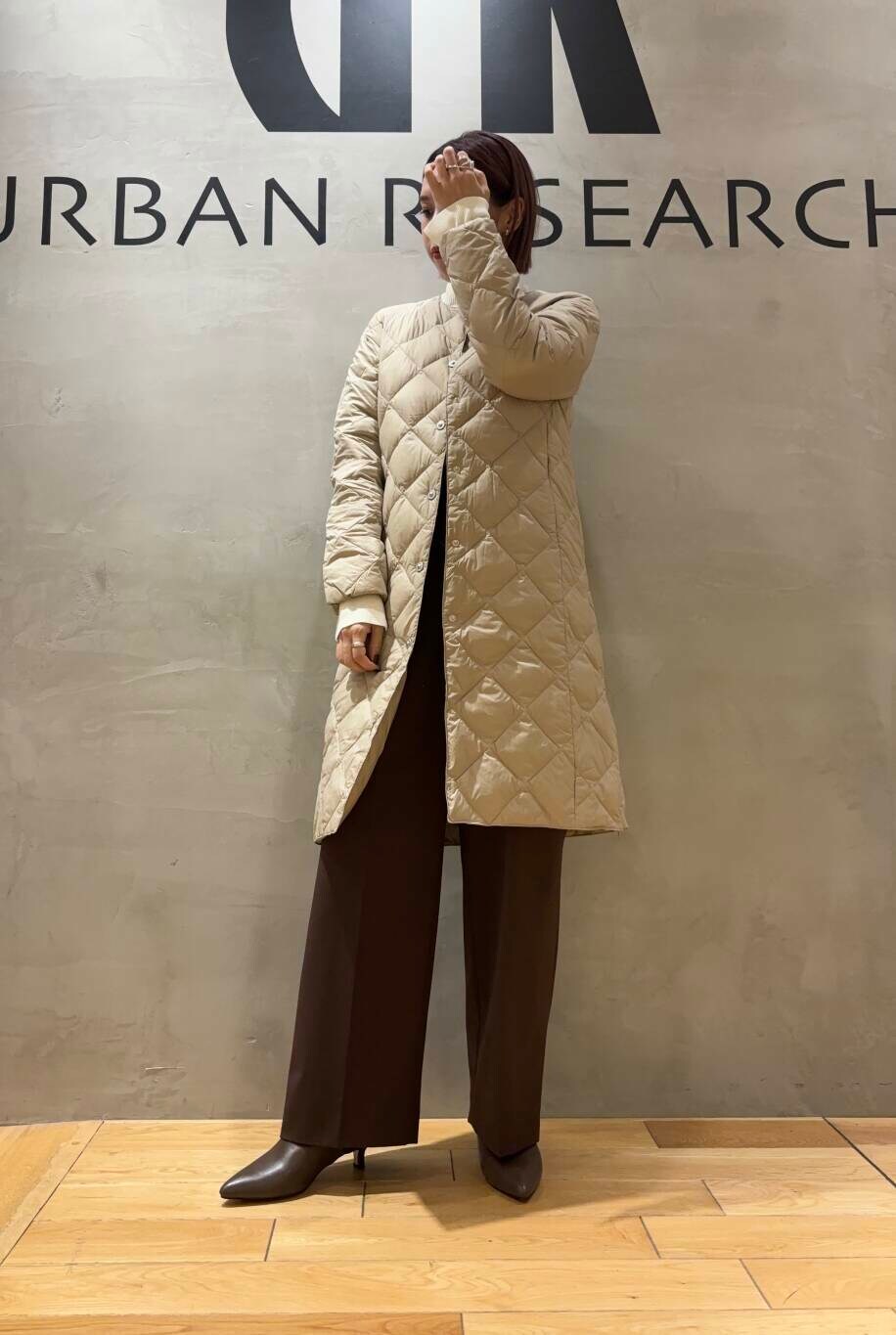 ホワイト系のニット/セーター、ブラウン系のその他パンツ、ベージュ系のダウンジャケット/コートを着用したレディースの秋コーディネートの3枚目の写真