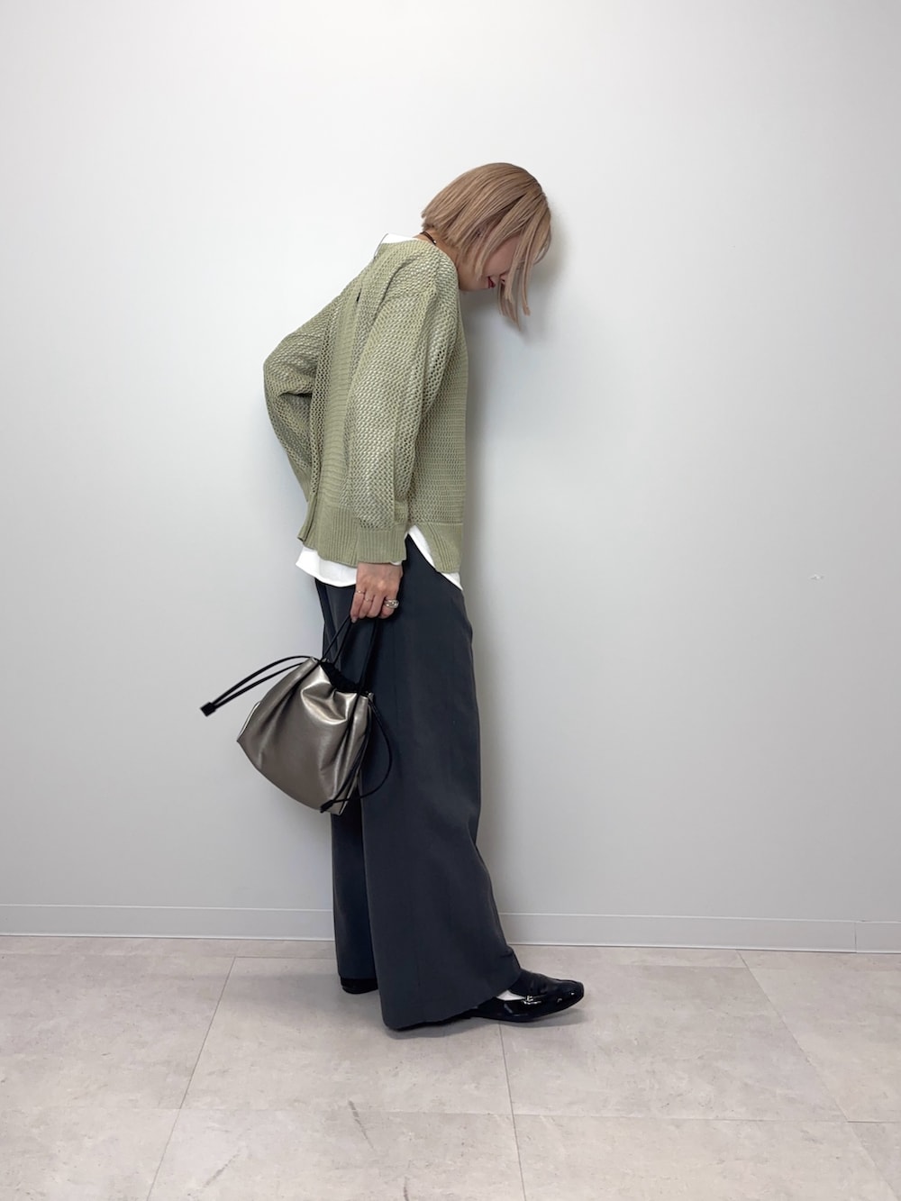 グリーン系のニット/セーター、グレー系のその他パンツ、シルバー系のショルダーバッグを着用したレディースの春コーディネートの4枚目の写真