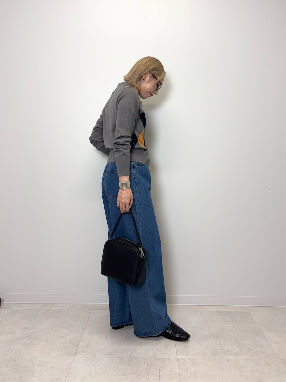 グレー系のカーディガン/ボレロ、ブルー系のデニムパンツ、ブラック系のショルダーバッグを着用したレディースの秋コーディネートの4枚目の写真