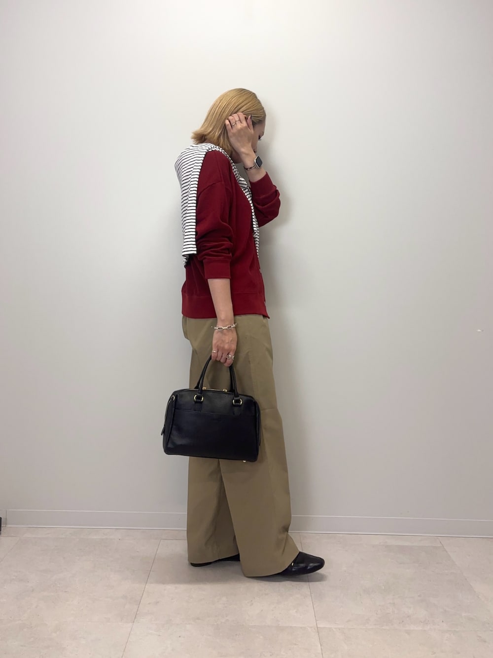 レッド系のカーディガン/ボレロ、ベージュ系のその他パンツ、ブラック系のボストンバッグを着用したレディースの秋コーディネートの5枚目の写真
