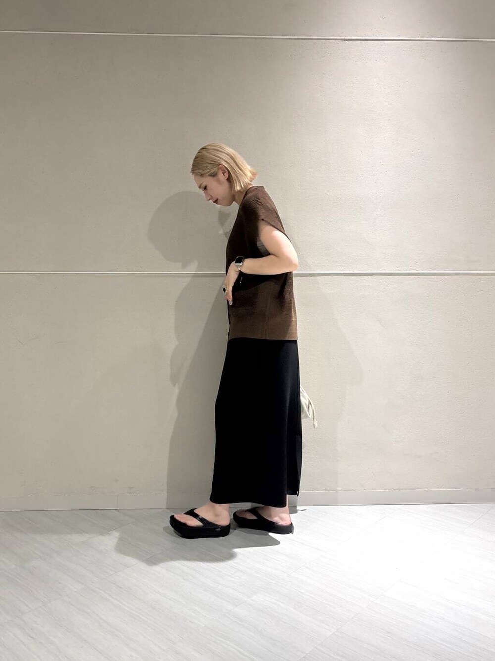 ホワイト系のキャミソール、ブラウン系のベスト、ブラック系のスカートを着用したレディースの夏コーディネートの2枚目の写真