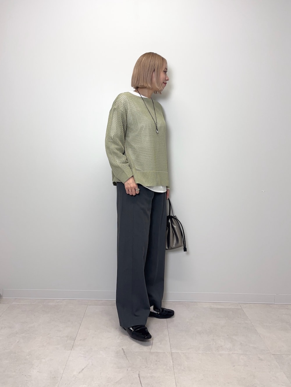 グリーン系のニット/セーター、グレー系のその他パンツ、シルバー系のショルダーバッグを着用したレディースの春コーディネートの3枚目の写真