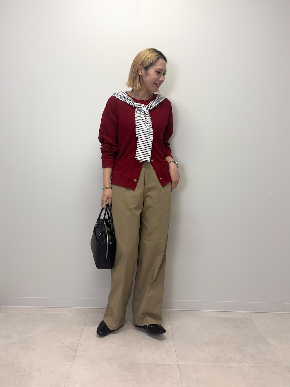 レッド系のカーディガン/ボレロ、ベージュ系のその他パンツ、ブラック系のボストンバッグを着用したレディースの秋コーディネートの4枚目の写真
