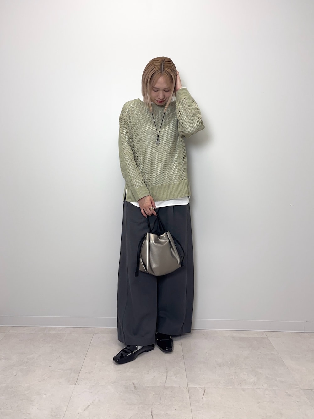 グリーン系のニット/セーター、グレー系のその他パンツ、シルバー系のショルダーバッグを着用したレディースの春コーディネートの5枚目の写真