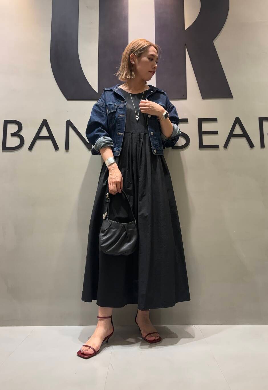 ブラック系のワンピース、ブルー系のデニムジャケットを着用したレディースの夏コーディネートの3枚目の写真