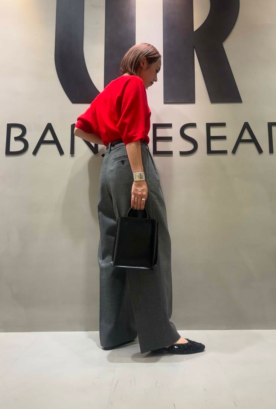 ブラック系のトートバッグ、グレー系のその他パンツ、レッド系のニット/セーターを着用したレディースの秋コーディネートの2枚目の写真