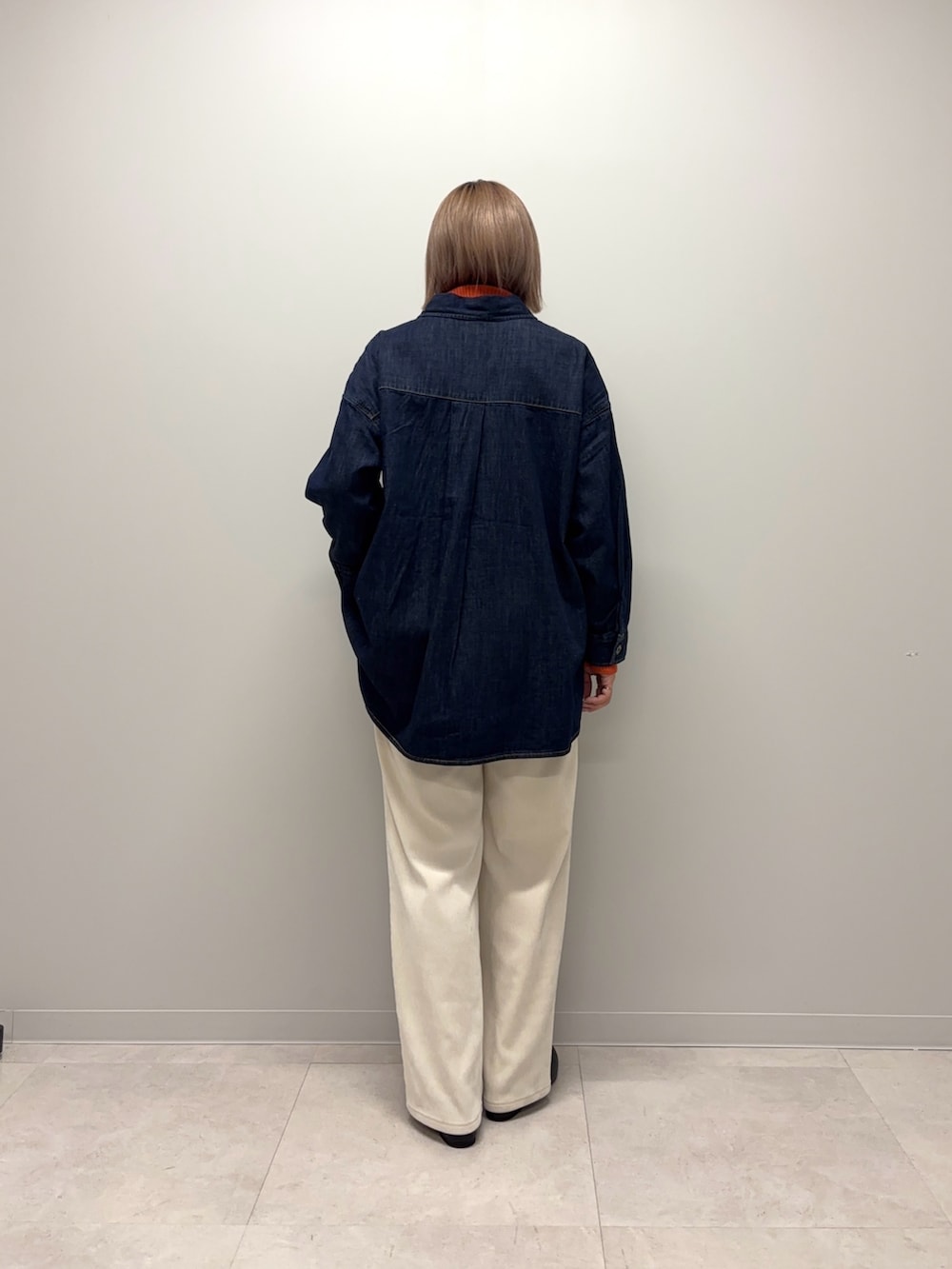 オレンジ系のニット/セーター、ブルー系のシャツ/ブラウス、ホワイト系のその他パンツを着用したレディースの冬コーディネートの4枚目の写真